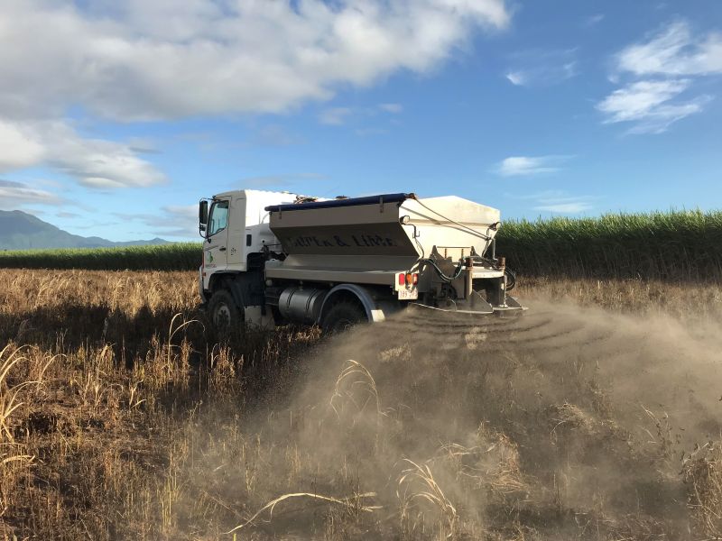 Truck spreading rock dust in field